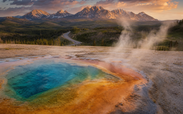 Yellowstone geothermal feature at golden hour with mountains and road
