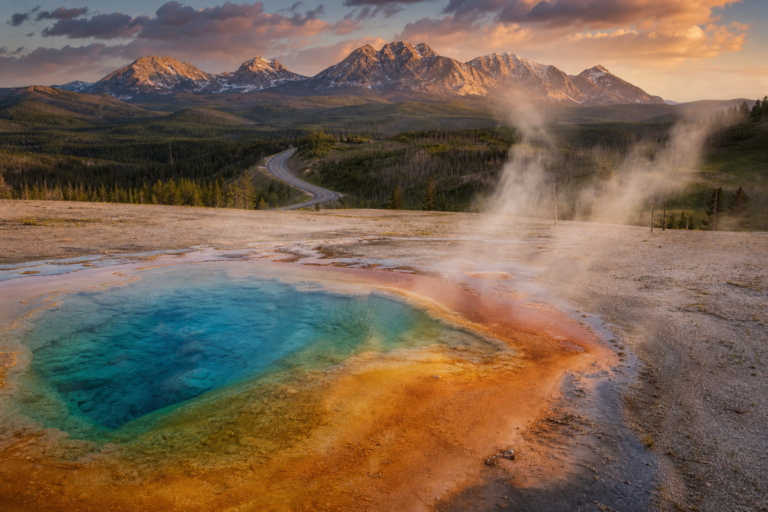 Yellowstone geothermal feature at golden hour with mountains and road